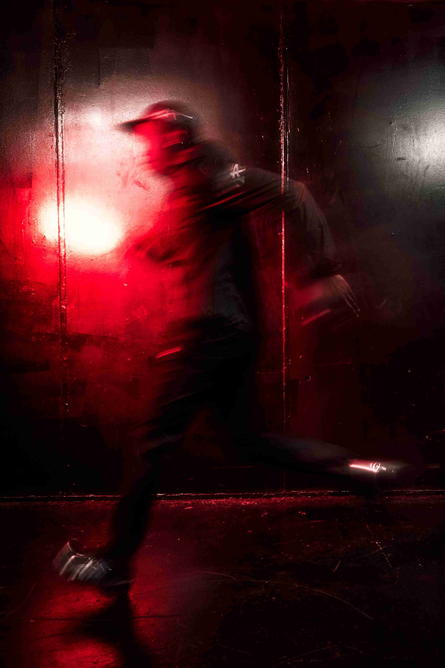 Silhouette en tenue streetwear noire et casquette, en mouvement sous une lumière rouge, pour un look Halloween 2026